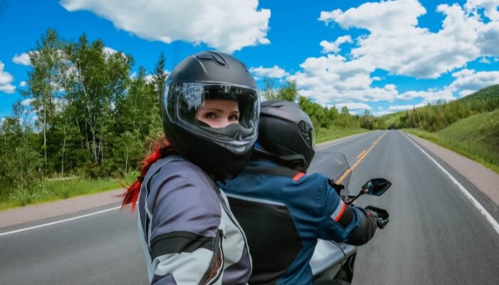 motarde bien équipée portant casque intégral et blouson de protection en été